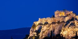 The Parthenon on top of a rocky mountain at night