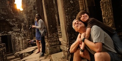 A dad and son view ancient ruins with other tourists nearby
