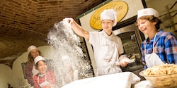 A Chef sprinkles flour as he teaches 3 children how to make strudel