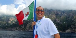 An Adventure Guide stands near water with a flag