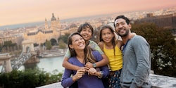 A family of Guests pose for a picture with a wide view of the city's historic buildings behind them