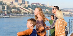 A family of Guests gaze out over the water as they ride a boat past the majestic buildings onshore