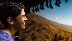 A young male Guest smiling while he experiences Soarin’ Around the World in Future World at Epcot