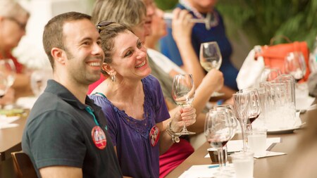 A man and a woman smile while sampling wine at a tasting event