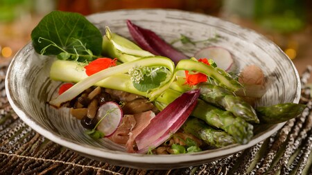 An asparagus and prosciutto salad with endive and olives in a bowl