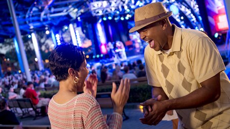 A man and a woman smile at each other in excitement while enjoying an open air concert