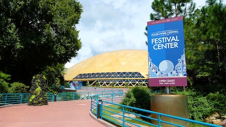 A man and 3 women smile while holding drinks and small plates of food