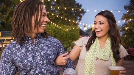 A young couple smiles while enjoying beer and outdoor festivities