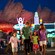 A family of four walks hand-in-hand through Cars Land in Disney California Adventure Park at night