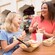 A smiling mother and daughter enjoy meals at an outdoor table