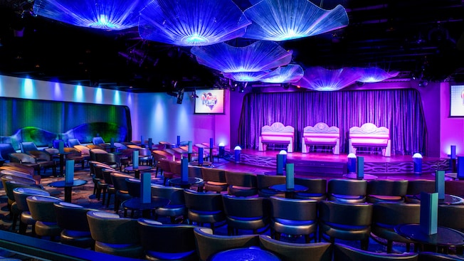 A showroom has several rows of lounge chairs curved around a curtained stage