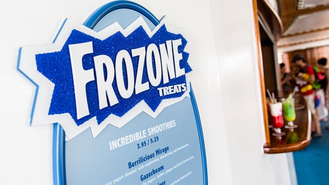 Two frozen drinks sit on a counter by a sign that says, Frozen Treats, and lists tasty smoothie options
