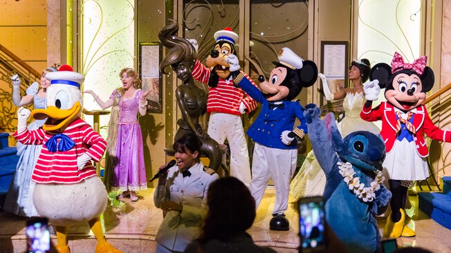 Donald, Goofy, Mickey, Minnie and other characters wave to the audience during a musical production