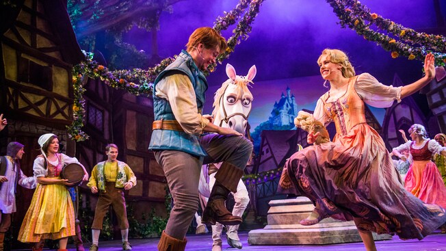 Rapunzel and bandit Flynn Rider dance onstage while horse Maximus looks on