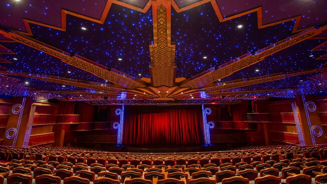 A long velvet curtain covers the stage in a the wonderous Walt Disney Theatre with many rows of seats