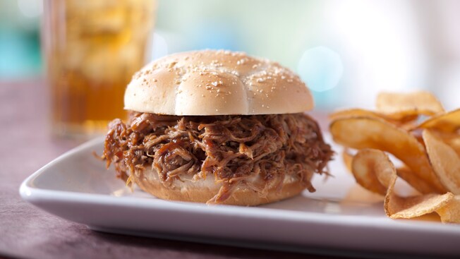 A barbecue pork sandwich served with potato chips
