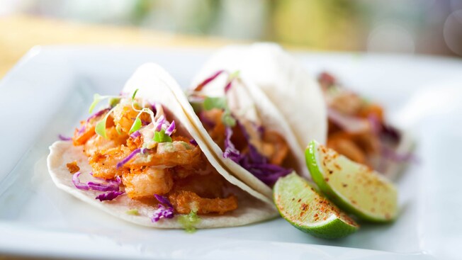 Limes sprinkled with chile-lime salt accompany a trio of tacos filled with crispy shrimp and cabbage