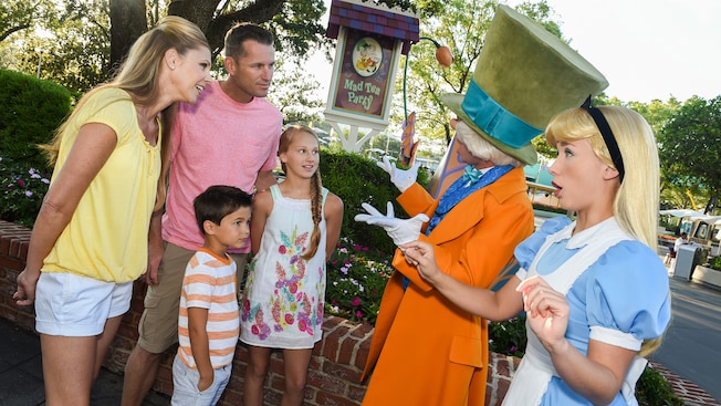 Characters From Alice In Wonderland At Mad Tea Party Walt Disney A Family Speaks With The Mad Hatter And Alice Near Sign That Reads Tea