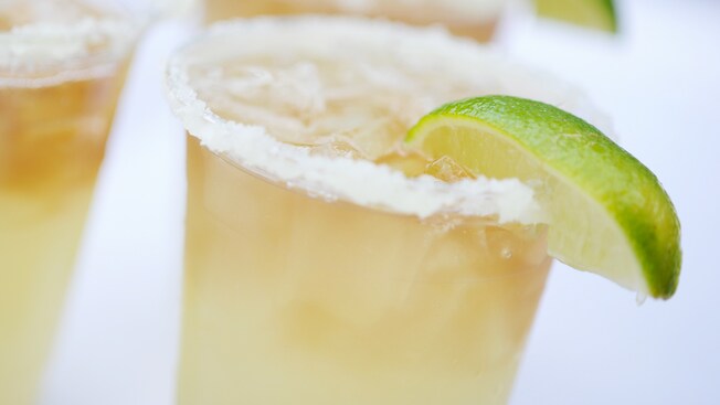 An icy margarita garnished with a slice of lime and served in a glass with a lightly salted rim