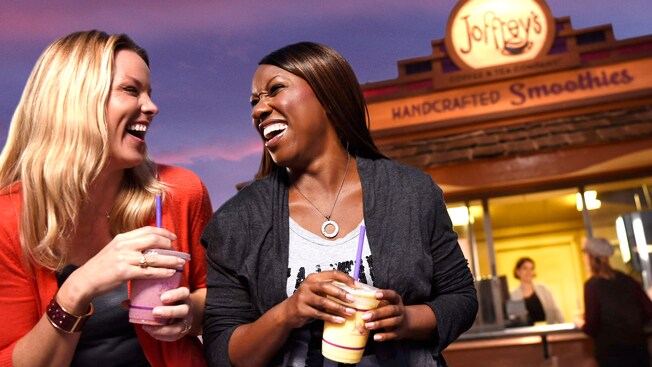 2 women share a laugh together while enjoying smoothies outside a handcrafted smoothie venue