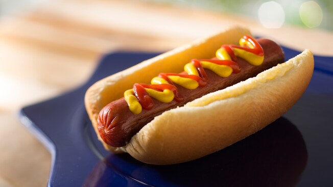 A hot dog in a bun topped with mustard and ketchup