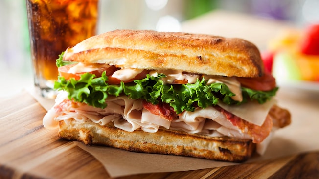 An Earl of Sandwich sandwich with turkey, bacon, lettuce, tomato and sauce on a roll