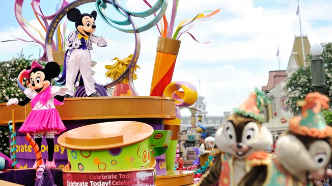 Mickey Mouse and Minnie Mouse on a parade float with Chip 'n Dale walking in front at the Celebrate A Dream Come True Parade