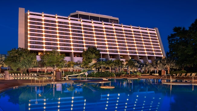 A poolside view of the rear of Disney's Contemporary Resort, lit up at night
