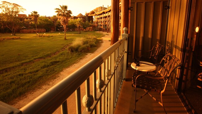 A balcony with 2 chairs and a table, overlooking the savanna