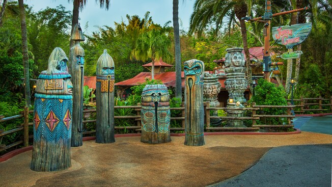 Colorfully painted tiki totems and sign stand on a patio outside the Jungle Cruise