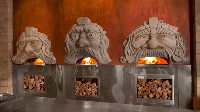 Three wood-fired ovens with comical faces whose mouths show the oven flames