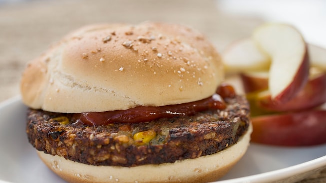 Vegetable burger on a bun with apple slices on the side