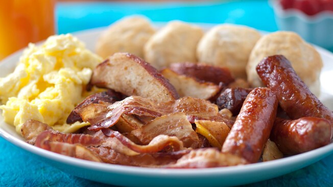 Breakfast plate of pork sausage links, smoked bacon, biscuits and scrambled eggs