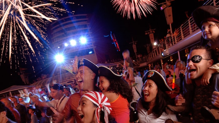 A audience dressed as Pirates of the Caribbean characters marvel at the fireworks going off overhead