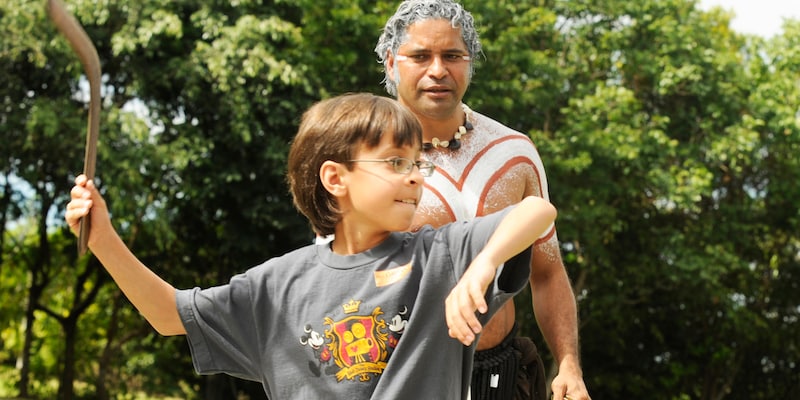 An aboriginal watches a boy throw a boomerang