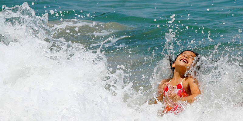 Waves splash a young girl playing in the surf