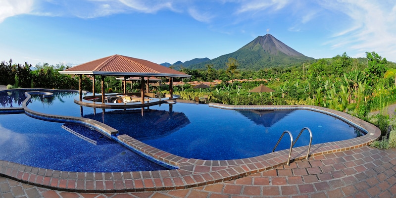 The pool at the Hotel Arenal Manoa with a swim-up bar in the middle and view of Arenal Volcano in the distance