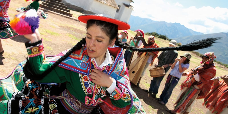 A woman wearing a traditional costume dances while a traditional band plays A woman wearing a traditional costume dances while a traditional band plays