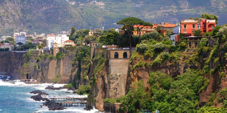 Buildings line steep cliffs that overlook a sea