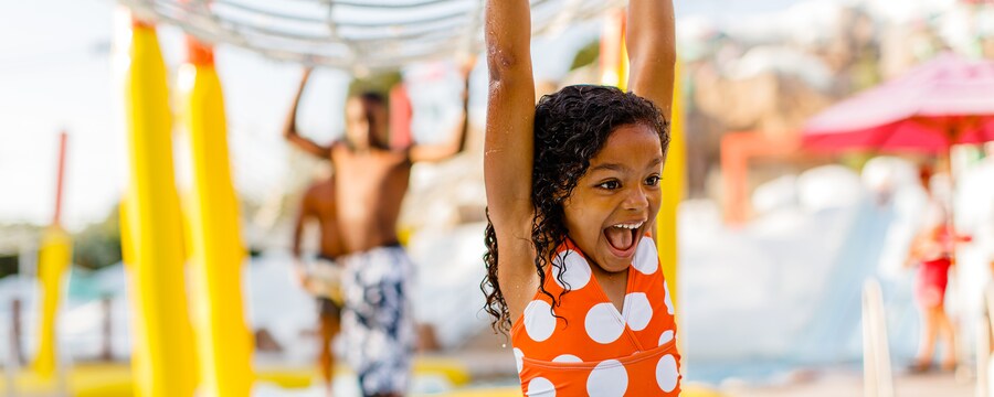 A young girl in a swimsuit smiles in a water park