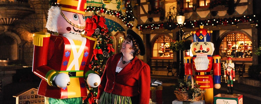A woman smiling at a human-sized toy-soldier statue in an Epcot Holiday celebration